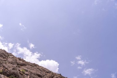 Arka planda mavi gökyüzü olan bir dağ. Gökyüzü açık ve güneş parlıyor.