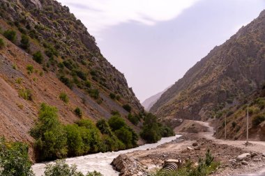 İçinden nehir akan bir dağ sırası. Nehir küçük ve dağlar yüksek.