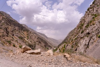 Bulutlu bir gökyüzü olan kayalık bir dağ vadisi. Gökyüzü bulutlu ve vadi kayalarla dolu.