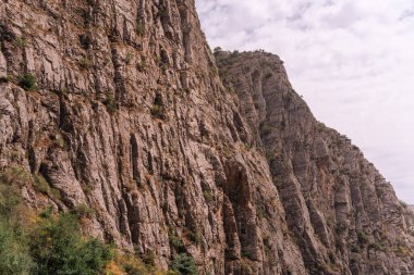 Üzerinde birkaç ağaç büyüyen kayalık bir dağ. Dağ kayalarla kaplı ve kayalık, çorak bir görünüşü var.