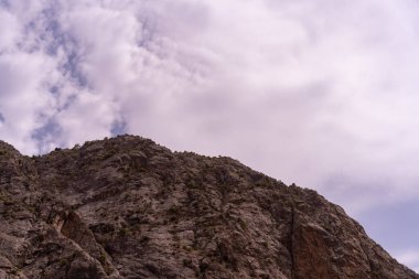 Arkasında bulutlu bir gökyüzü olan bir dağ. Gökyüzü mavi ve griden bir karışımdır, karamsar ve kaygı verici bir görüntü verir.