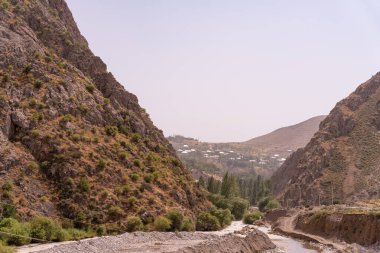 İçinden nehir akan bir dağ sırası. Dağlar ağaçlarla kaplı ve nehir kayalık.