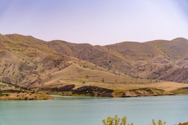 Önünde göl olan güzel bir dağ sırası. Dağlar çimlerle kaplı ve göl sakin ve berrak. Sahne huzurlu ve sakin, dağlarla birlikte.