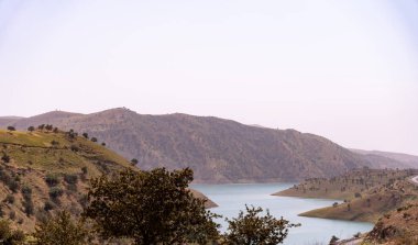 İçinden nehir akan bir dağ sırası. Gökyüzü açık ve güneş parlıyor.