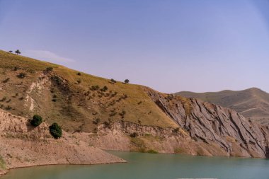 Önünde bir su kütlesi olan bir dağ sırası. Su koyu mavi bir renktir.