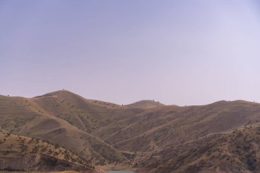 Gökyüzü açık ve dağlar yeşil çimlerle kaplı.