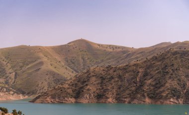 Önünde göl olan bir dağ sırası. Dağlar ağaçlarla kaplı ve göl sakin ve berrak. Huzurlu ve huzurlu bir sahne.
