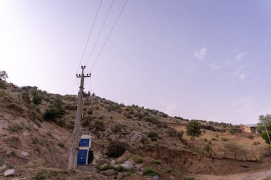 Üstünde mavi bir tuvalet olan bir direk. Gökyüzü mavi ve güneş görünmüyor.