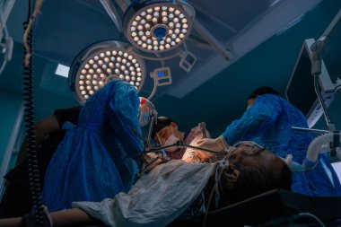 Bir grup cerrah bir hastaya ameliyat yapıyor. Cerrahlar hastanın hayatını kurtarmak için çalışırken atmosfer gergin ve ciddi.