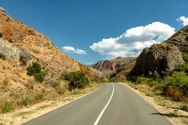 Arka planda dağ olan bir yol. Yol boş ve gökyüzü mavi.