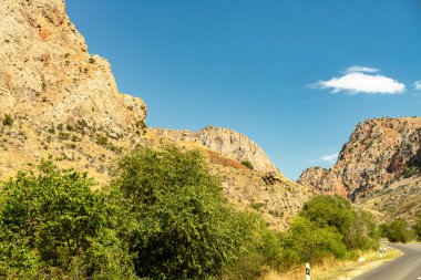 İçinden yol geçen bir dağ sırası. Yol boş ve gökyüzü temiz.