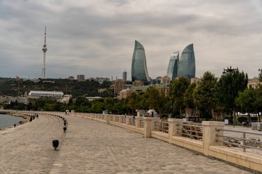 Arka planda büyük bir bina ve yüksek bir kulesi olan bir şehir. Şehir sular altında ve ağaçlarla dolu bir parkı var.