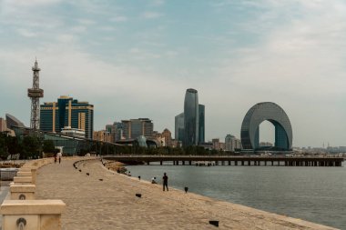 Arka planda büyük bir bina ve ön planda bir iskele olan bir şehir. İskele kıvrımlı ve su sakin.