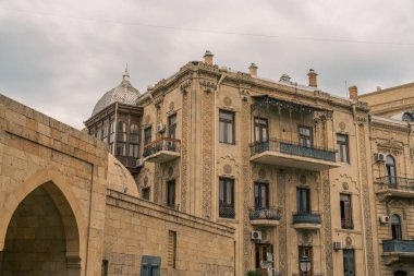 Balkonlu ve tepesinde kubbe olan bir bina. Bina eski ve bir sürü penceresi var.