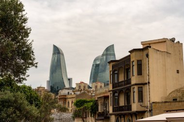 Yüksek binaları ve bulutlu gökyüzü olan bir şehir manzarası. Binalar eski ve eşsiz bir mimari tarzı var.