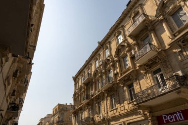 Üzerinde Penti yazan binalı bir cadde. Binanın balkonları var ve çok yüksek.