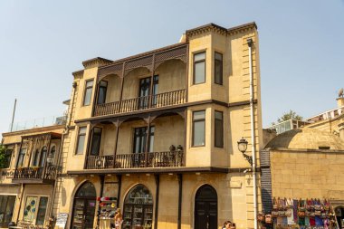 Balkonu ve bir sürü penceresi olan büyük bir bina. Bina kahverengi ve çok detay içeriyor.