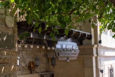 Üzerinde Arapça yazı olan bir tabela bir binanın üzerinde asılı. İşaret yabancı bir dilde ve dış yüzeyi taş olan bir binada.