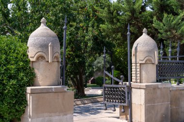 Kapı taş ve metalden yapılmıştır. Kapı bir ağacın önünde.