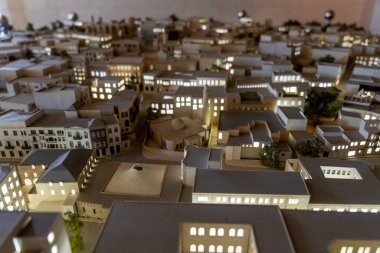 Merkezinde büyük bir bina bulunan bir şehrin modeli. Şehir geceleri ışıldıyor, sıcak ve davetkar bir atmosfer sağlıyor.