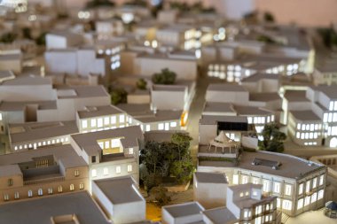Bir sürü binası ve ağacı olan bir şehrin modeli. Şehir geceleri ışıldıyor, sıcak ve davetkar bir atmosfer sağlıyor.