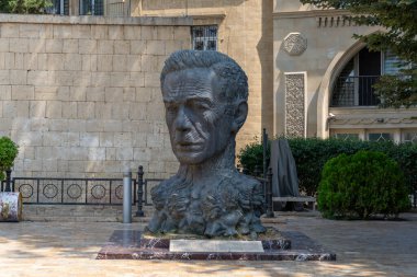 Bir adamın kafasının heykeli bir binanın önünde sergileniyor. Heykel bronzdan yapılmıştır ve eşsiz bir tasarıma sahiptir. Heykel tuğla bir duvarla çevrili mermer bir levhaya yerleştiriliyor.