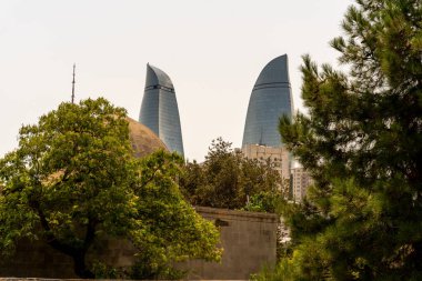 Arasında yeşil ağaç olan iki uzun bina.