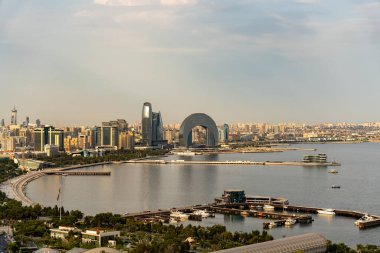 Ortasında büyük bir bina ve büyük bir su kütlesi olan bir şehir. Su sakin ve gökyüzü bulutlu.