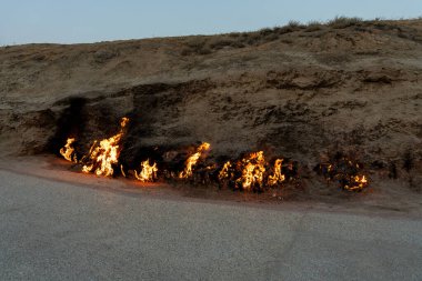 Toprakta bir ateş yanıyor. Yangın çok büyük ve yol kenarındadır.