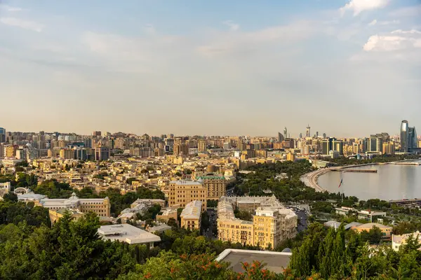 Arka planda büyük bir su kütlesi olan bir şehir manzarası. Şehir yüksek binalarla dolu ve gökyüzü açık.
