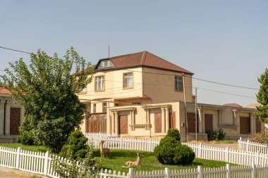 Önünde beyaz çitleri olan büyük bir ev. Ev boş ve bir sürü penceresi var.