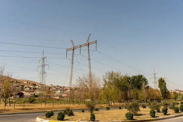 Birkaç ağaç ve birkaç elektrik hattı olan bir kırsal bölge. Gökyüzü açık ve güneş parlıyor.