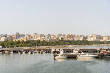 Arka planda büyük bir su kütlesi olan bir şehir. Yat limanında bir sürü tekne var.