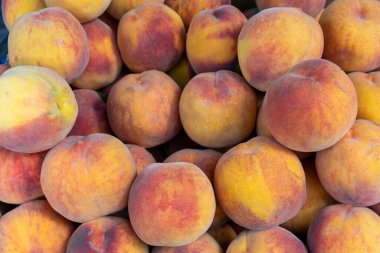 Bir demet şeftali üst üste yığılmış. Şeftaliler bulanık ve kırmızımsı turuncu renkte.