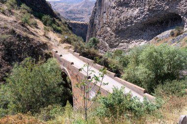 Vadinin üzerinde iki yanında ağaçlar olan bir köprü. Köprü taştan yapılmıştır ve oldukça dardır.