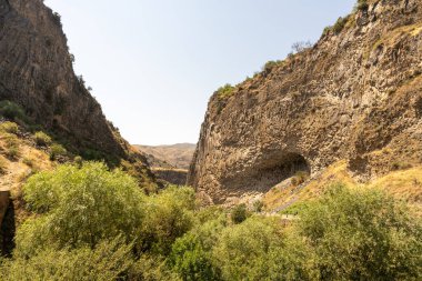 Aralarında vadi olan bir dağ sırası. Vadi ağaçlar ve çalılarla dolu. Gökyüzü açık ve parlak