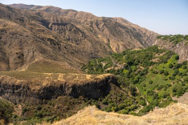 Aralarında vadi olan bir dağ sırası. Vadi ağaçlarla doludur ve dağlar çoraktır.