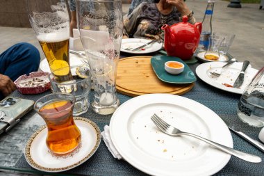 Birkaç tabak ve bir bardak birayla dolu bir masa. Masa yiyecek ve içeceklerle dolu ve çatal ve bıçak gibi birkaç alet edevat var. Sahne rahat ve rahat.