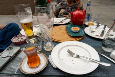 Birkaç bardaklı bir masa, çatallı bir tabak ve çaydanlık. Masa yiyecek ve içeceklerle dolu ve aile yemeği gibi görünüyor.