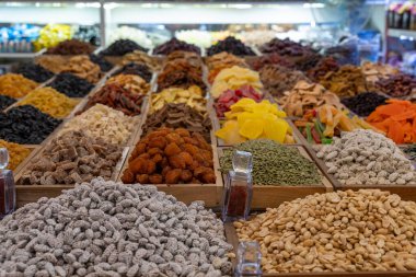 Bir mağazada çeşitli fındık ve tohumlar sergilenir. Fındıklar farklı şekil ve boyutlarda ve tohumlar farklı renklerde. Görüntü düzenli ve görsel olarak çekici.