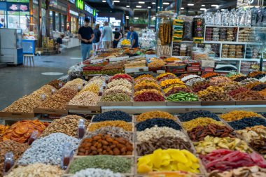 Çeşitli baharat ve fındıklardan oluşan geniş bir gösteri. Baharatlar birçok farklı konteynırda sıralanır ve fındıklar çeşitli yığınlar halinde yayılır. Sahne canlı ve renkli.