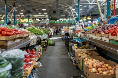 Birçok çeşit sebze ve meyve içeren büyük bir üretim pazarı. Pazar açık ve alışveriş yapan insanlarla dolu.