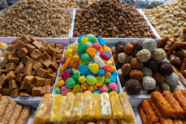 Bir masa dolusu fındık ve şeker. Fındıklar çeşitli şekil ve boyutlarda, ve şekerler renkli ve yüksek. Masa satılık.