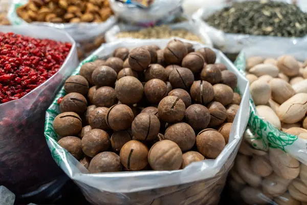 Bir torba fındık diğer fındık torbalarıyla aynı masada oturuyor. Fındıklar çeşitli boyutlarda ve şekillerde, ve hepsi farklı torbalarda toplanmış. Sahne bolluk ve çeşitlilik hissi veriyor.