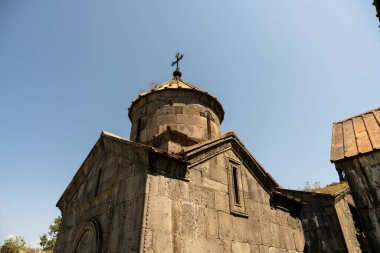 Çan kulesi ve tepesinde haç olan büyük bir bina. Binanın eski ve dış yüzeyi taştan. Gökyüzü açık ve mavi