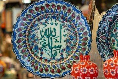 Üzerinde Allah 'ın sözü yazılı mavi bir tabak. Tabak çiçeklerle süslenmiş ve mavi bir kenarı var.