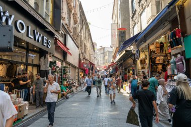 Yürüyen ve alışveriş yapan insanlarla dolu kalabalık bir cadde. Cadde Wolves adında bir dükkan da dahil olmak üzere dükkanlarla dolu.