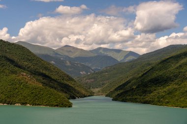 Ortasında göl olan güzel bir dağ sırası. Göl yemyeşil ağaçlar ve dağlarla çevrilidir. Gökyüzü açık ve mavi ve dağlar karla kaplı. Huzur dolu bir sahne.