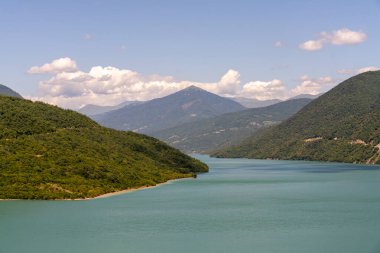 İçinden bir nehir akan güzel bir dağ sırası. Su sakin ve berrak, dağlar yemyeşil ağaçlarla kaplı. Huzurlu ve huzurlu bir sahne.