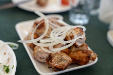 Üstünde soğan olan bir tabak kızarmış tavuk. Soğanlar dilimlendi ve tavuğun etrafına saçıldı.